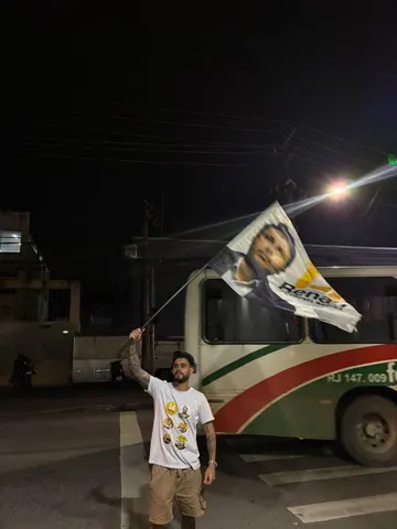Participante com bandeira ao lado de um ônibus, à noite