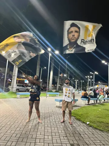 Participantes com bandeiras em um espaço público à noite