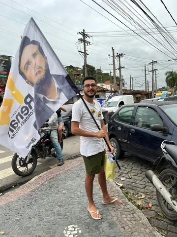 Participante com bandeira e material de campanha junto à rua