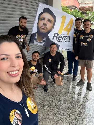 Grupo reunido com material de campanha diante de um comércio