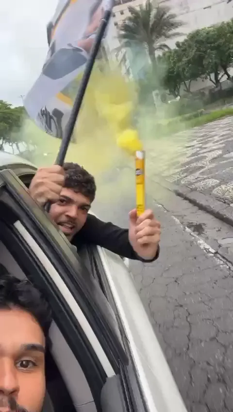 Registro da carreata a partir do interior de um veículo, com uma bandeira na janela